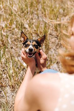 a woman holding a small dog in her hands