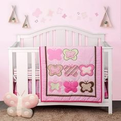 a baby crib with a pink and brown butterfly quilt on it's bed