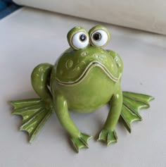 a green frog sitting on top of a white table