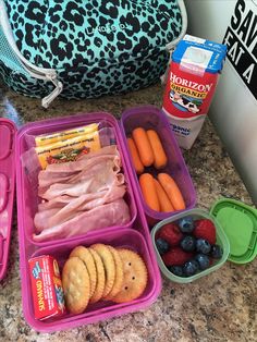 the lunch box is filled with fruit, crackers and meat