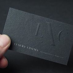 a hand holding up a business card with the letter n on it's side