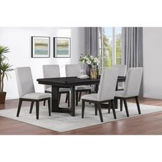 a dining room table with white chairs and a rug on the floor in front of it