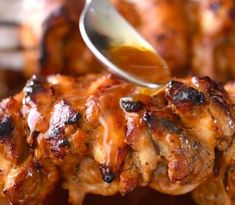 a spoon is being used to scoop bbq sauce onto chicken wings