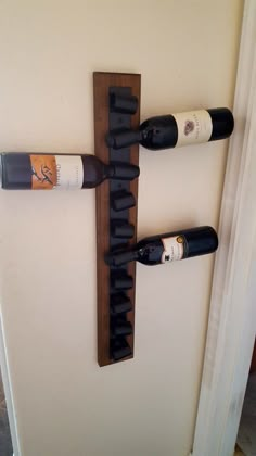 three wine bottles are hanging on the wall next to each other in a cross shape