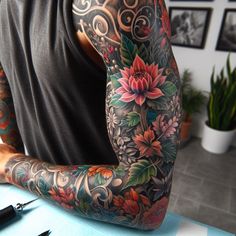 a tattooed man sitting at a table with his arm covered in tattoos and writing tools