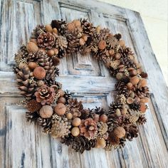 a wreath made out of pine cones and acorns on an old wooden door