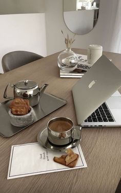 a laptop computer sitting on top of a wooden table next to a cup of coffee