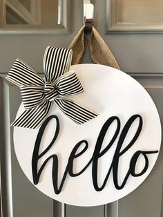 a door hanger with the word hello painted on it and a bow tied to it