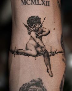 a tattoo on the leg of a person with an image of a cupid sitting on barbed wire