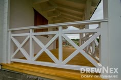 a porch with white railing and wood flooring on the side of a house that is painted white