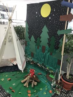 a teepee tent is set up in the middle of a room with trees and other decorations