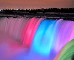 the rainbow colored water is flowing over the falls