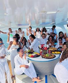 a large group of people on a boat with food and drinks in front of them