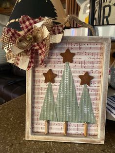 a wooden frame with two christmas trees on top of music sheets and burlocks