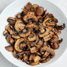 a white bowl filled with sliced mushrooms on top of a table