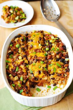 a casserole dish with black beans, cheese and green onions