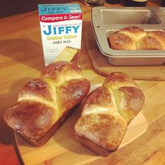 three loaves of bread sitting on top of a cutting board next to a box of jelly