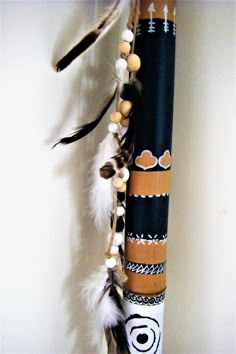 a decorative pole with feathers hanging from it's side and another piece of art on the wall behind it