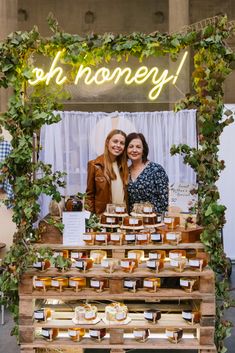 two women standing in front of a display of honey