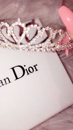 a tiara sitting on top of a book with the word queen dior written below it