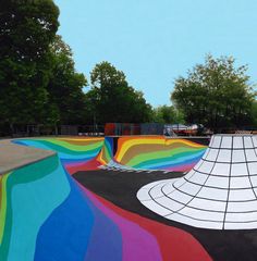 a skateboard park with colorful ramps and trees in the background