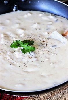 a skillet filled with white sauce and garnished with parsley