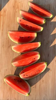 several slices of watermelon on a wooden cutting board with the tops cut off