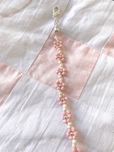 a pink and white beaded necklace on a quilt