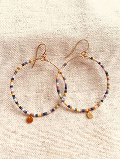 This listing is for one pair of beaded hoop earrings.  The beads are Miyuki Delicas Japanese glass beads.  Bead colors: Blue, Turquoise, baby blue, light pink, mauve, ochre  The ear wire and hoop wire are gold filled.  The gold blank charm that dangles at the bottom of the hoop is gold vermeil.  These earrings are light on the earlobe and add a pretty pop of color and movement!  Measurement: from the top of the ear wire to the bottom of the vermeil round charm is 2 1/4 inch.  What is Gold Filled Small Hoop Beaded Earrings For Everyday, Colorful Round Beads Earrings For Everyday, Colorful Beaded Earrings For Everyday, Colorful Round Bead Earrings For Everyday, Gift Small Hoop Beaded Earrings With Tiny Beads, Everyday Round Beaded Earrings, Gift Hoop Earrings With Dangling Beads, Hoop Beaded Earrings With Spacer Beads, Hoop Earrings With Tiny Beads