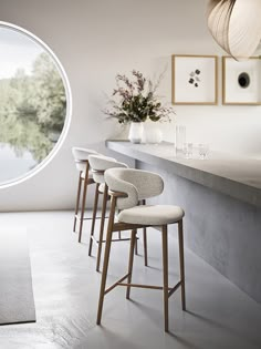 four stools are lined up in front of a bar with a circular window and artwork on the wall