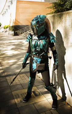 a person in a blue and black costume standing next to a wall