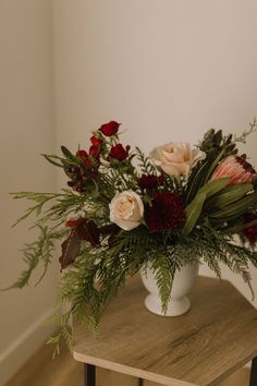 a white vase filled with flowers on top of a wooden table