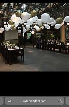 a large room with tables and chairs covered in white paper lanterns hanging from the ceiling