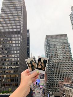 a person holding up two photos in front of some tall buildings