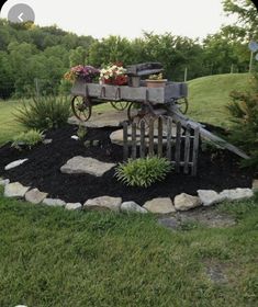 the barn porch is surrounded by black mulch and rocks, with an old wagon as a planter