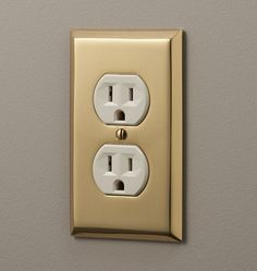 an electrical outlet on the wall with two outlets and one light switch is shown in gold