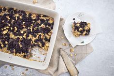 blueberry crumble cake in a white dish next to a plate with a fork