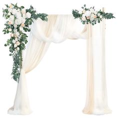 a white wedding arch decorated with flowers and greenery