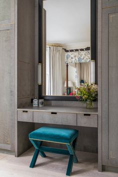 a blue stool sits in front of a gray vanity with a large mirror above it