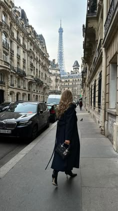 a woman is walking down the street in paris