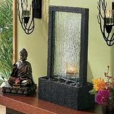 a buddha statue sitting on top of a wooden table next to two wall sconces