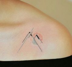 a woman's shoulder with an abstract tattoo on it