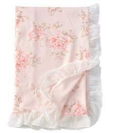 a pink blanket with white ruffles and roses on the bottom is laying down