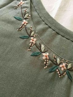 an embroidered t - shirt with flowers and leaves on it