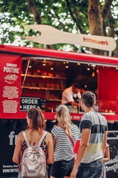 three people standing in front of a food truck