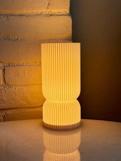 a white lamp sitting on top of a table next to a brick wall and floor