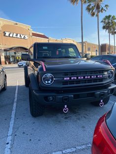 the front end of a black truck parked in a parking lot next to other cars