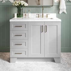 a bathroom with green walls and white countertops, two mirrors above the sink and flowers in vases on the cabinet