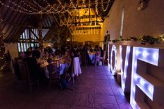 people sitting at tables in a large room with lights on the ceiling and decorations hanging from the ceiling