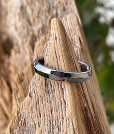 a close up of a ring on top of a piece of wood with trees in the background